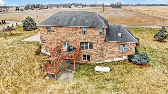 back of house with brick siding, a patio, a wooden deck, and a lawn