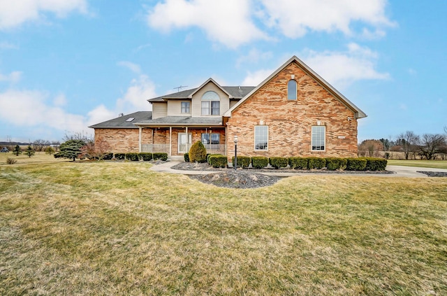 traditional-style home with covered porch, a front yard, and brick siding