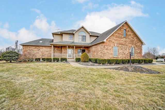 traditional home featuring covered porch, a front yard, and brick siding