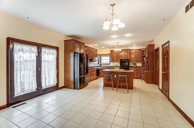 kitchen featuring visible vents, a kitchen island, hanging light fixtures, an inviting chandelier, and black appliances