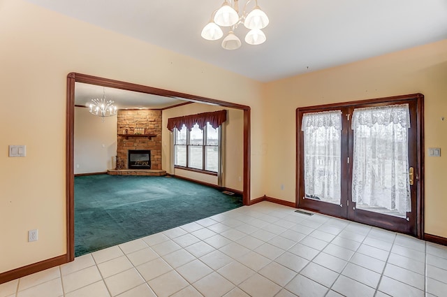 unfurnished living room with light tile patterned floors, visible vents, light colored carpet, a fireplace, and a notable chandelier