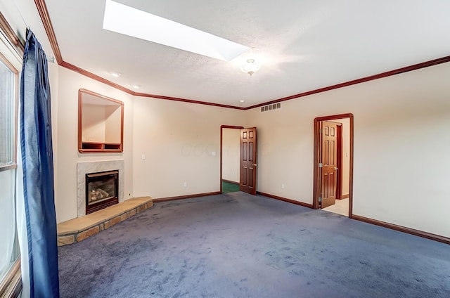 unfurnished living room with carpet floors, a skylight, crown molding, visible vents, and a premium fireplace