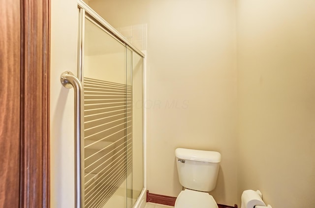 bathroom with a shower stall and toilet