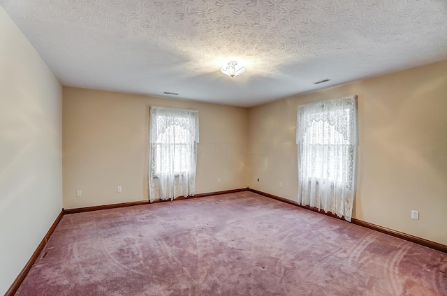 unfurnished room featuring carpet floors, visible vents, a textured ceiling, and baseboards