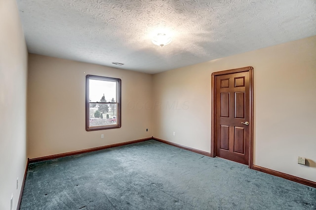 carpeted spare room featuring a textured ceiling, visible vents, and baseboards