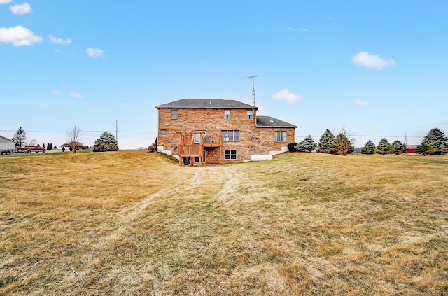 back of house with brick siding and a yard