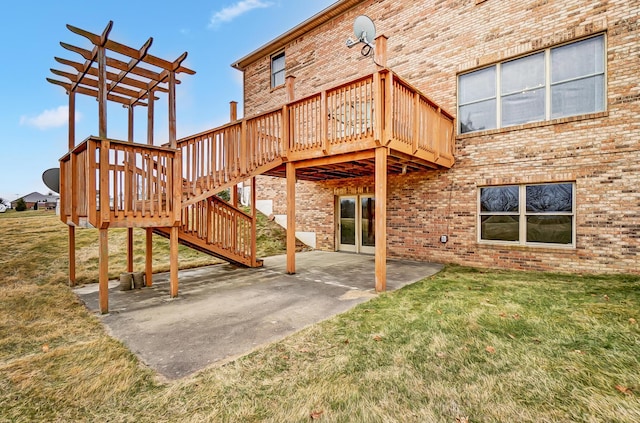 back of property featuring a deck, a yard, brick siding, and a patio area