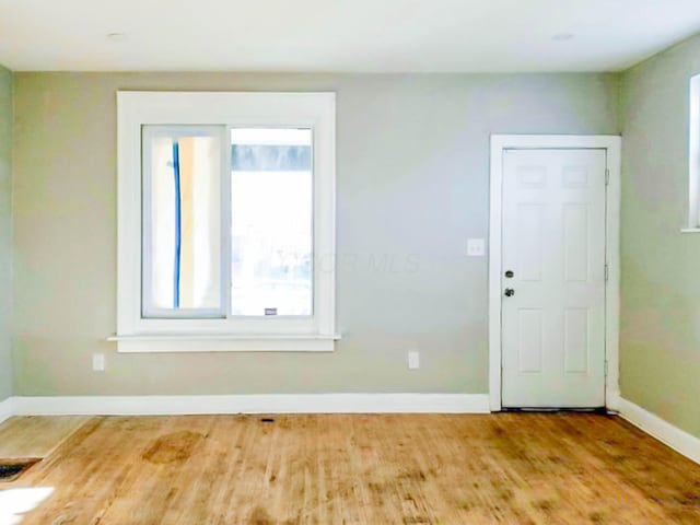 empty room featuring wood finished floors, visible vents, and baseboards