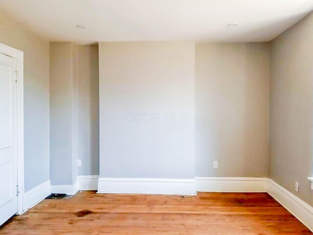 spare room featuring baseboards and wood finished floors