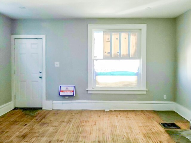 spare room featuring visible vents, baseboards, and wood finished floors