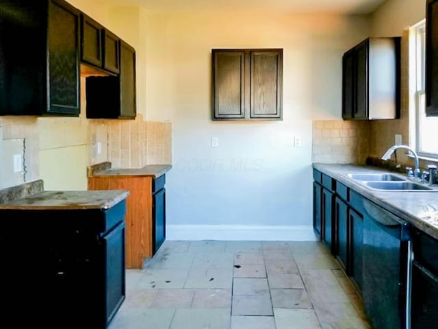 kitchen with black dishwasher, baseboards, a sink, and decorative backsplash