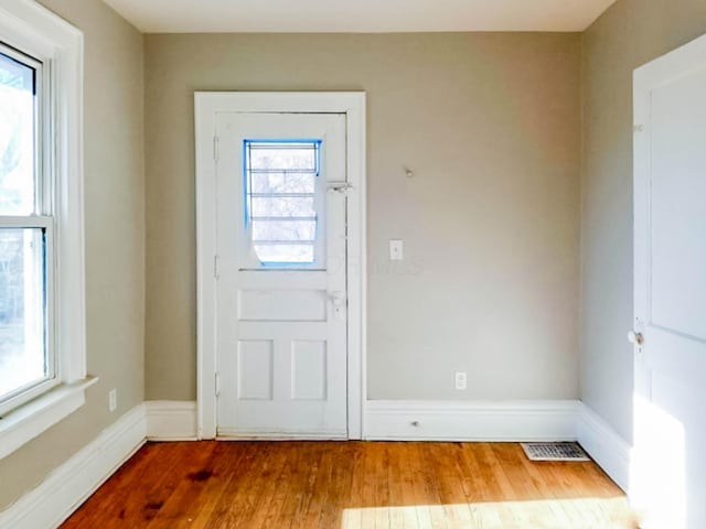 foyer with baseboards, visible vents, and wood finished floors