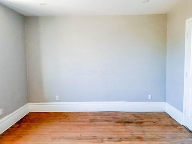 unfurnished room with baseboards and wood finished floors