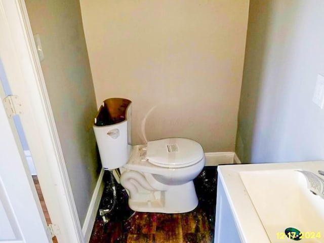 half bathroom with baseboards, a sink, and toilet