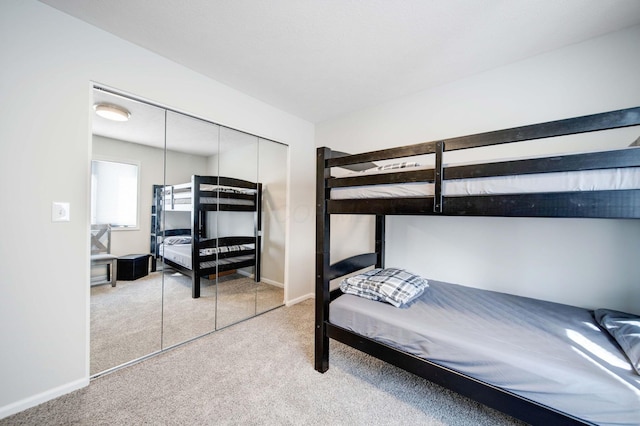 bedroom featuring baseboards, a closet, and light colored carpet