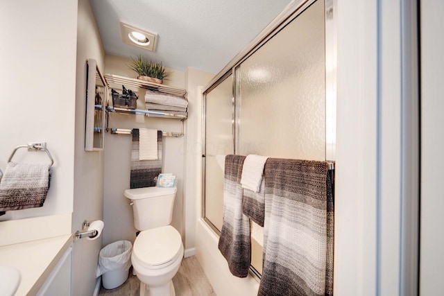 bathroom with bath / shower combo with glass door, vanity, toilet, and wood finished floors