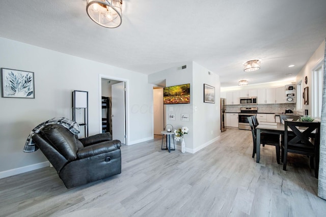 living area featuring visible vents, light wood-style flooring, and baseboards