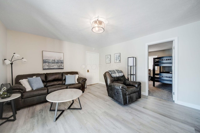 living room featuring light wood finished floors, baseboards, and a textured ceiling