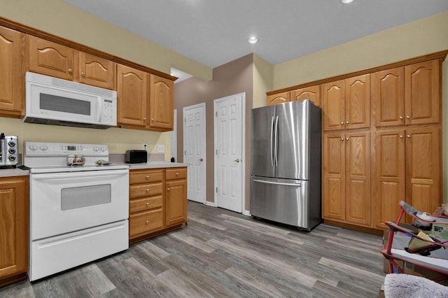 kitchen featuring light countertops, white appliances, and wood finished floors