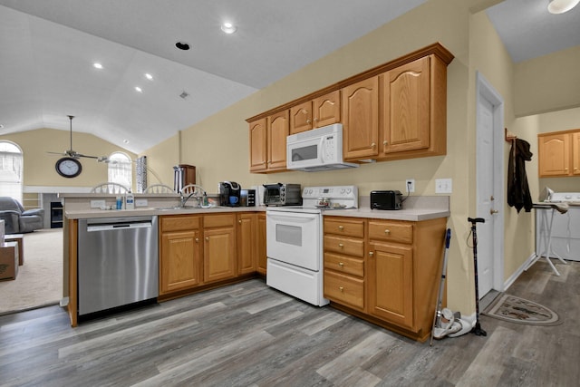 kitchen featuring white appliances, lofted ceiling, open floor plan, light countertops, and a sink