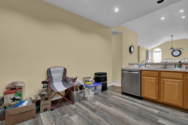 kitchen featuring light countertops, light wood-style flooring, stainless steel dishwasher, brown cabinetry, and vaulted ceiling