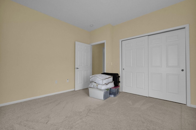 unfurnished bedroom featuring a closet, light colored carpet, and baseboards