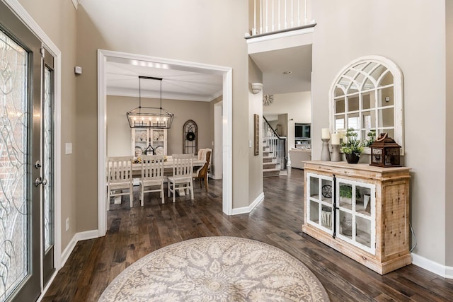 foyer entrance with dark wood-style floors, crown molding, baseboards, and stairs