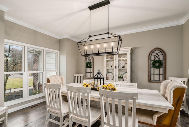 dining space featuring dark wood-type flooring, visible vents, ornamental molding, and an inviting chandelier