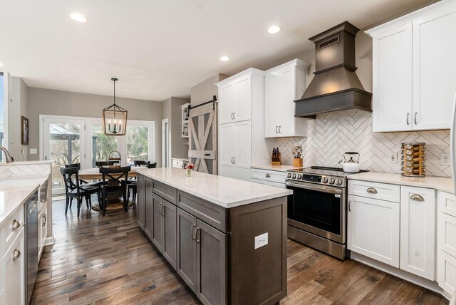 kitchen featuring premium range hood, appliances with stainless steel finishes, white cabinets, and a barn door