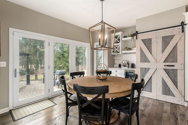 dining space featuring an inviting chandelier, a barn door, baseboards, and wood-type flooring