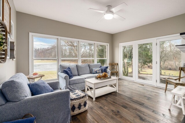 living room with dark wood-style floors, a wealth of natural light, and a ceiling fan