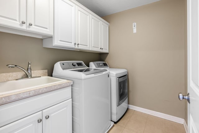 laundry room with cabinet space, baseboards, washer and clothes dryer, a sink, and light tile patterned flooring