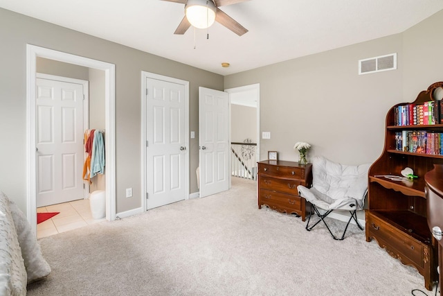 living area featuring an upstairs landing, visible vents, carpet flooring, and a ceiling fan