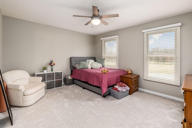 bedroom featuring light carpet, a ceiling fan, and baseboards