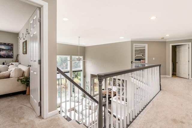 hall featuring ornamental molding, carpet flooring, an upstairs landing, and baseboards