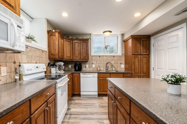 kitchen featuring brown cabinets, dark countertops, visible vents, a sink, and white appliances