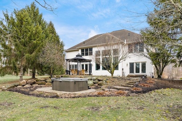 back of house featuring a gazebo, a lawn, and a hot tub