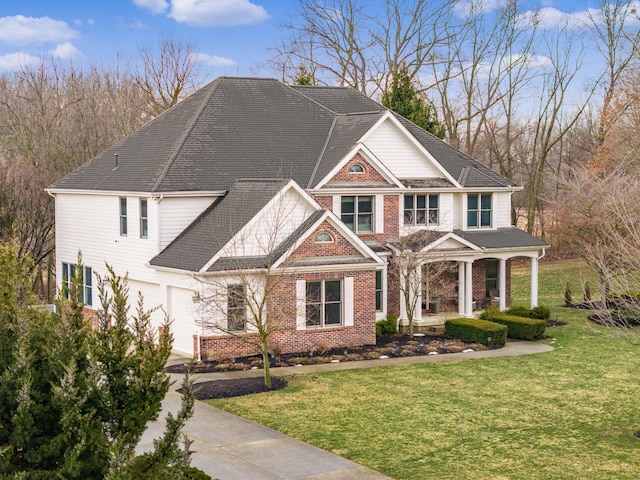 view of front facade featuring a garage, driveway, covered porch, a front lawn, and brick siding