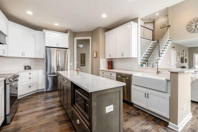 kitchen featuring stainless steel appliances, white cabinetry, a sink, and dark wood-type flooring