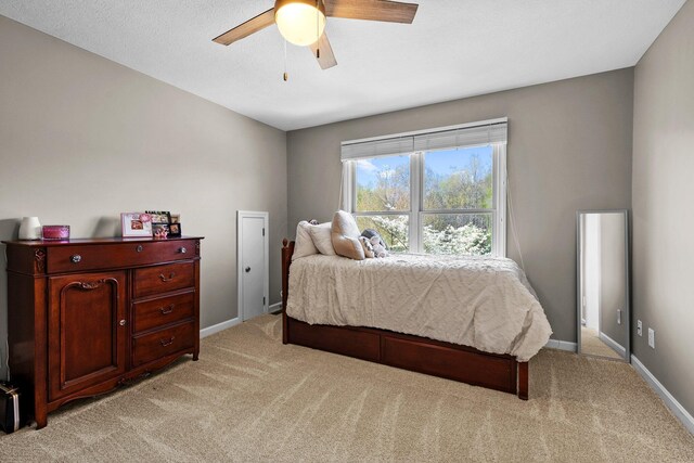 bedroom featuring light colored carpet, baseboards, and ceiling fan