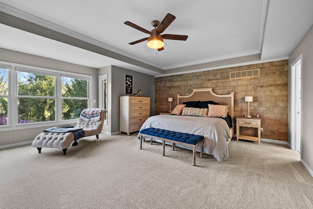 carpeted bedroom with visible vents, crown molding, wood walls, baseboards, and ceiling fan