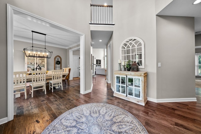 foyer featuring baseboards, wood finished floors, and a chandelier