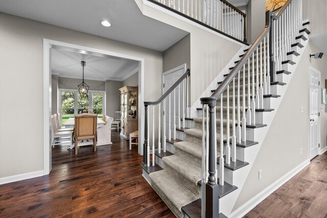 stairway featuring ornamental molding, wood finished floors, baseboards, recessed lighting, and a notable chandelier