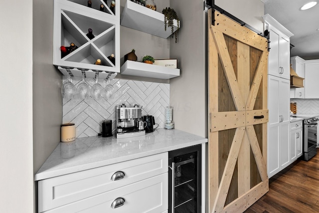 bar featuring beverage cooler, dark wood-type flooring, a barn door, tasteful backsplash, and stainless steel electric range oven