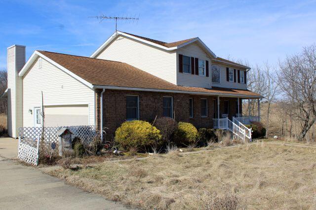 view of home's exterior with a garage, brick siding, driveway, and a chimney