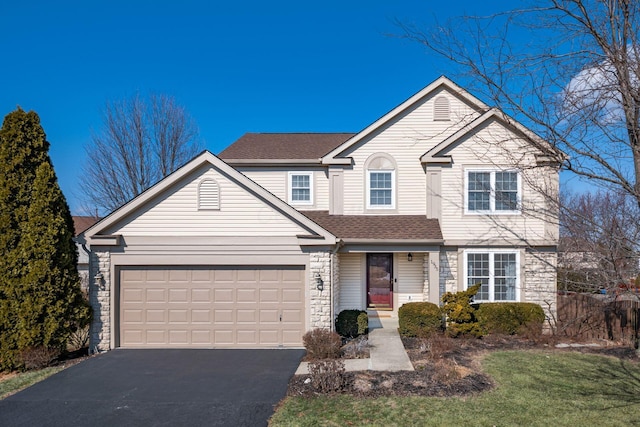 traditional-style home with stone siding, roof with shingles, driveway, and an attached garage