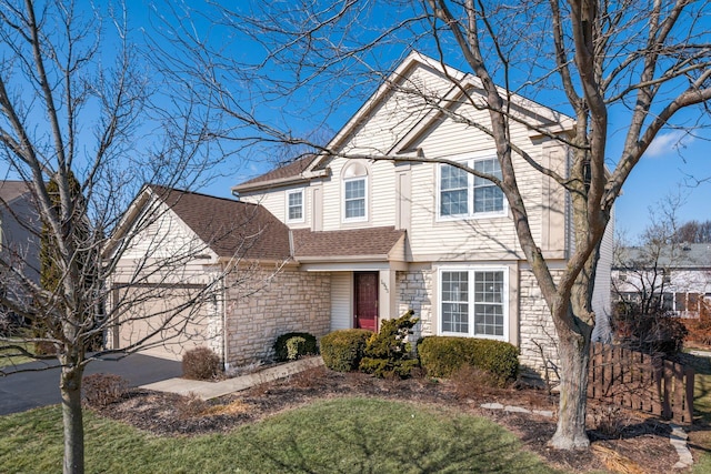 traditional home featuring a garage, stone siding, a shingled roof, and driveway