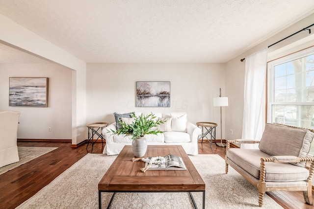 living area featuring a textured ceiling, wood finished floors, and baseboards