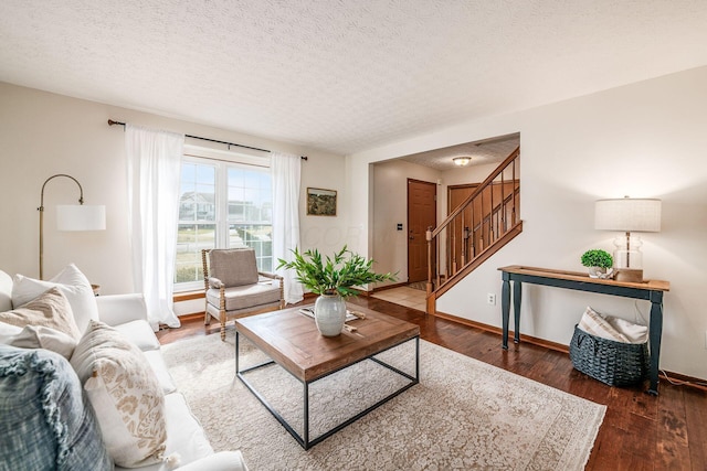 living area with wood finished floors, a textured ceiling, baseboards, and stairs