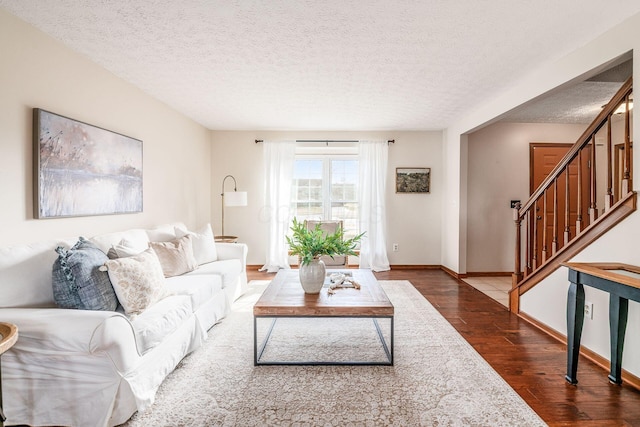 living room featuring a textured ceiling, stairway, wood finished floors, and baseboards